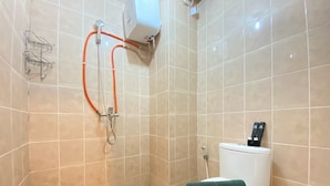 Et badeværelse med toilet, brusebad og en håndtørrer.