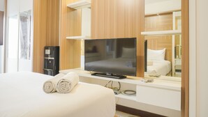 A hotel room with a large bed, a flat-screen TV, a mirror, and wooden paneling.