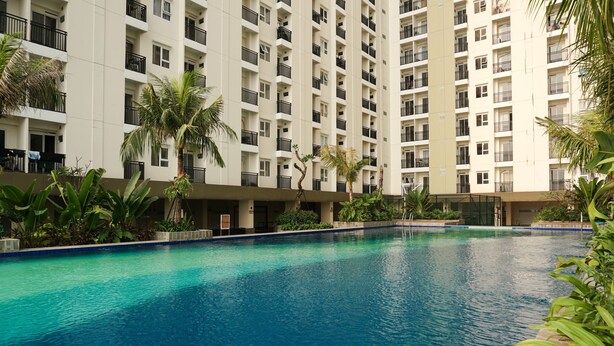 A swimming pool surrounded by a multi-story residential building with balconies.