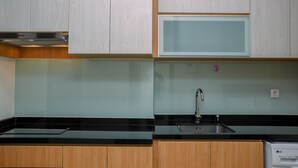 A kitchen with wooden cabinets, a black countertop, a stainless steel sink, and an LG dishwasher. - Great Deal And Comfy Studio At Menteng Park Apartment (Jakarta)