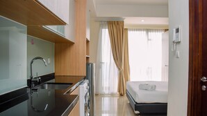 A modern hotel room with a kitchen area, a bed, and a bathroom. - Great Deal And Comfy Studio At Menteng Park Apartment (Jakarta)