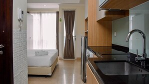 Quarto de hotel com cama, banheiro, área de cozinha e porta para o banheiro.