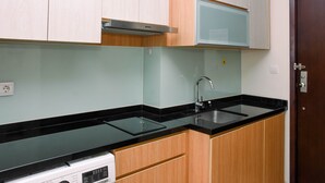 Uma cozinha com bancada preta, armários de madeira, coifa de aço inoxidável e micro-ondas.