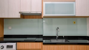 Cozinha com armários de madeira, coifa de aço inoxidável, micro-ondas, pia e máquina de lavar.
