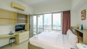 Hotelkamer met een bed, een bureau met een televisie, een stoel en een raam met uitzicht op de stad.