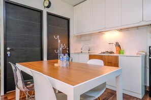 Eine moderne Küche mit weißen Schränken, einem Holztisch und einem klaren Stuhl.