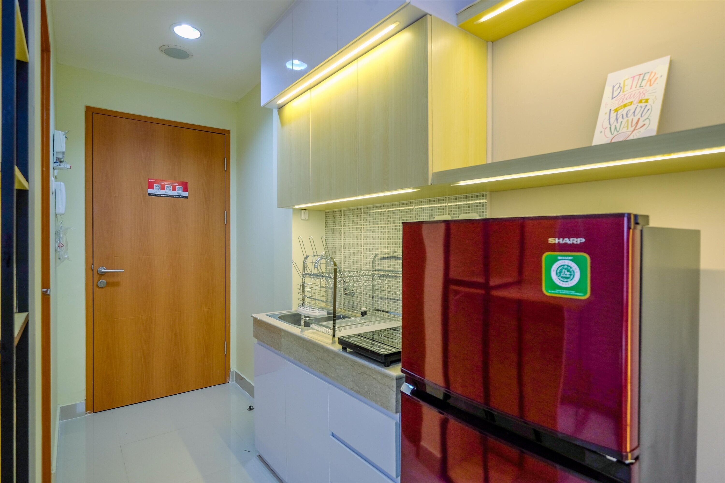 A modern kitchen with a red refrigerator, a wooden door, and a tiled backsplash.
