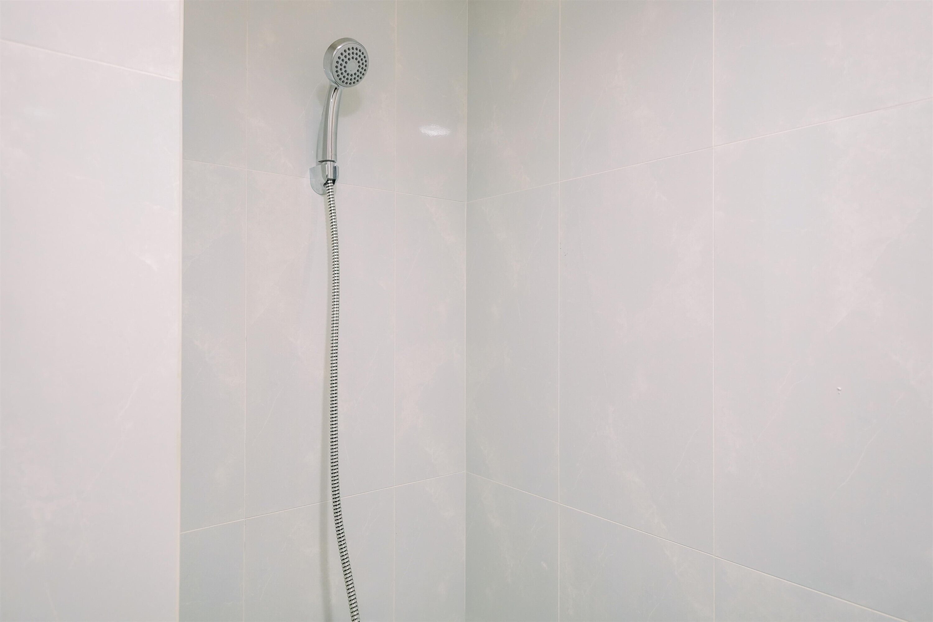 Una ducha con cabezal de ducha de mano y manguera flexible.