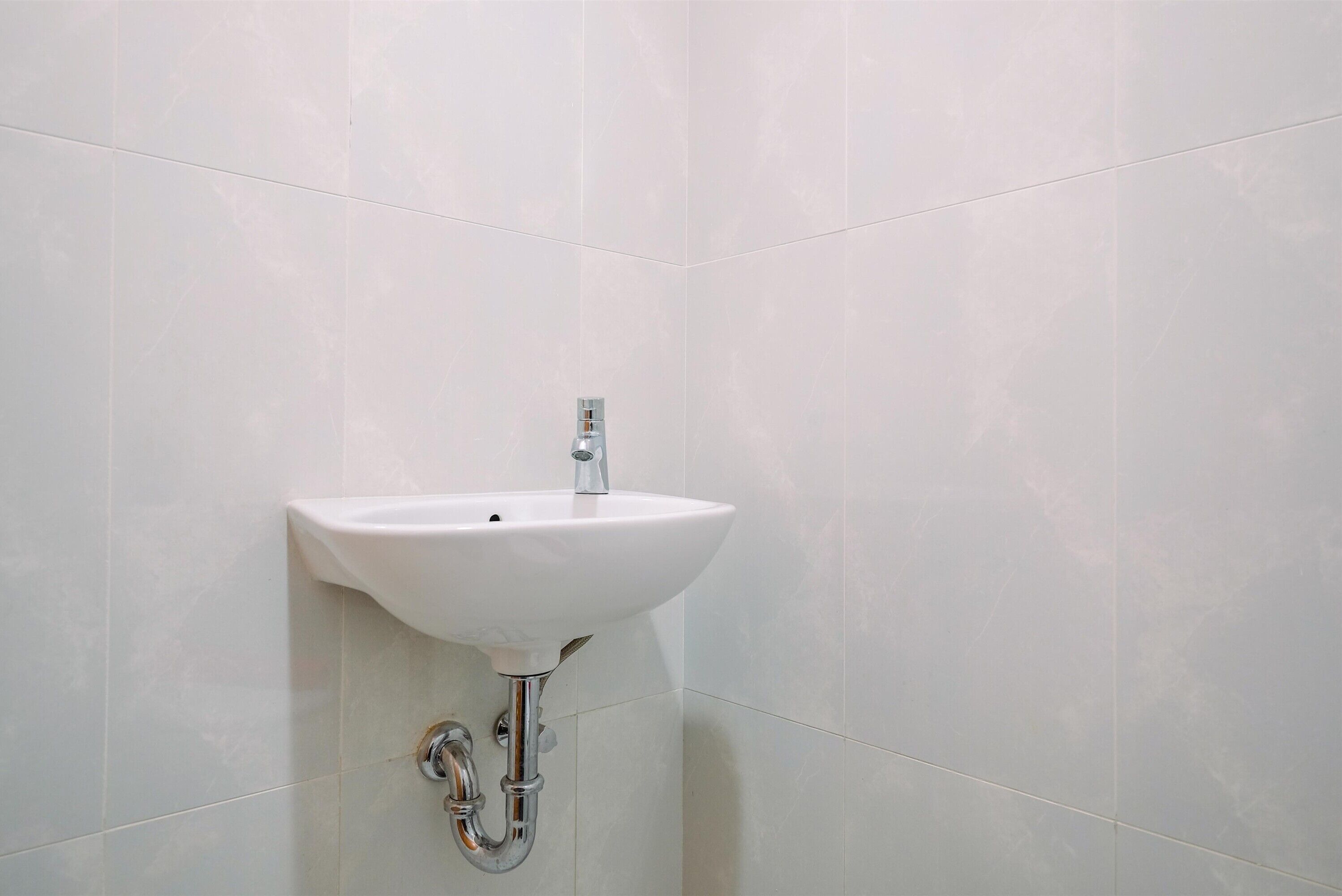 A bathroom with a white sink mounted on a tiled wall.