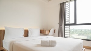 A hotel room with a large bed, a desk, and a view of the city. - Fully Furnished With Pleasure 2Br At Sky House Bsd Apartment (Pagedangan)