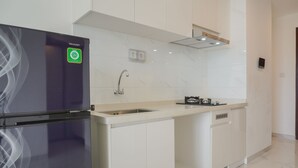 A modern kitchen with white cabinetry, a stainless steel refrigerator, a sink, and a stove. - Fully Furnished With Pleasure 2Br At Sky House Bsd Apartment (Pagedangan)