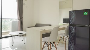 A modern hotel room with a dining area, a refrigerator, and a view of the city. - Fully Furnished With Pleasure 2Br At Sky House Bsd Apartment (Pagedangan)