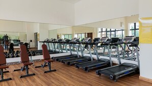 A gym with treadmills, weight benches, and a large mirror. - Fully Furnished With Pleasure 2Br At Sky House Bsd Apartment (Pagedangan)