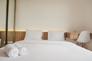 Une chambre d’hôtel avec un lit bien fait, deux oreillers, une table de chevet avec une lampe et deux serviettes enroulées.