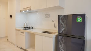 A modern kitchen with white cabinetry, a stainless steel refrigerator, a gas stove, and a built-in dishwasher.