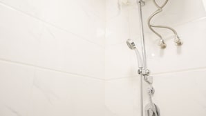 A shower with a handheld showerhead and a wall-mounted faucet.