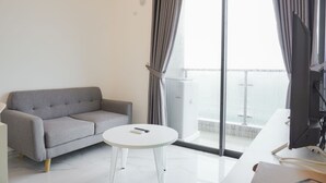 A modern room with a grey sofa, a small white table, and a large window with curtains.