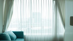 A room with a sofa and sheer curtains.