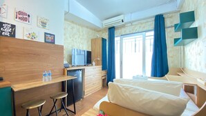 Quarto de hotel compacto com cozinha compacta, sofá-cama, pequena mesa de jantar e televisão.
