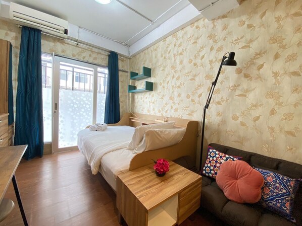 Une chambre à coucher avec un lit, un bureau, un canapé et une lampe.