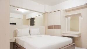 A modern bedroom with a bed, bedside table, wardrobe, and a mirror. - Comfort Studio At Kebagusan City Apartment (Jakarta)