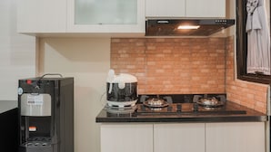 A compact kitchen with a coffee machine, a rice cooker, and a gas stove. - Comfort Studio At Kebagusan City Apartment (Jakarta)