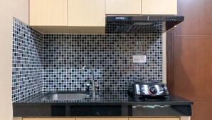 Eine Küche mit schwarzem Fliesenrückwand, Spüle aus Edelstahl und einer schwarzen Arbeitsplatte.