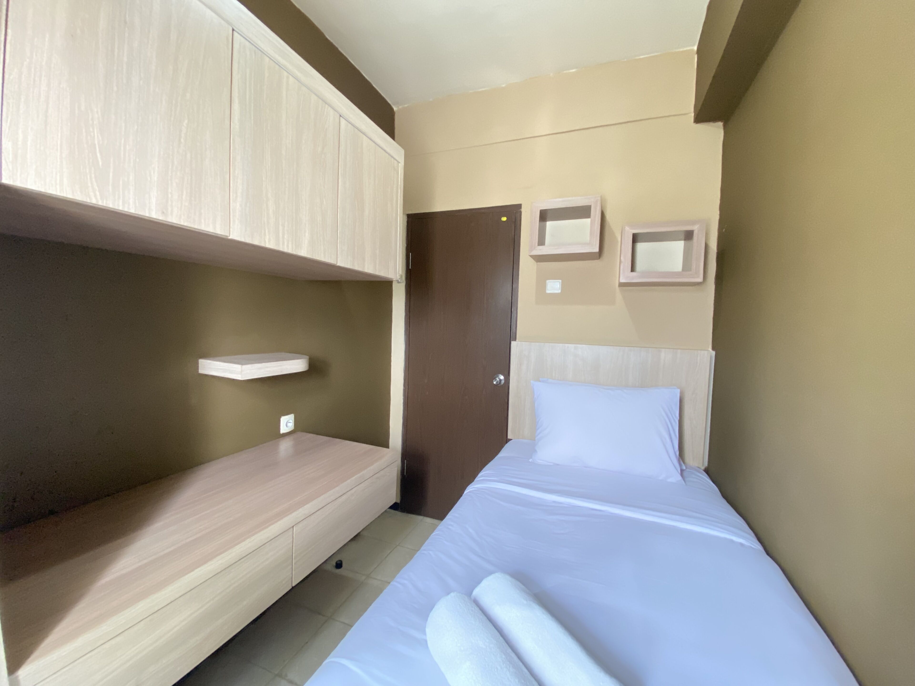 Ein Schlafzimmer mit einem Bett, einer Holzbank, einem kleinen Regal und einer Tür.