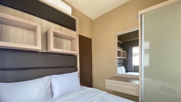 Une chambre d’hôtel moderne dotée d’un grand lit, d’une tête de lit intégrée et d’une armoire-miroir.