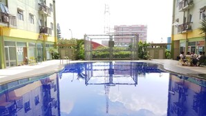 Une piscine entourée d’immeubles dotés de balcons, un ciel dégagé et une tour qui se profile à l’horizon.