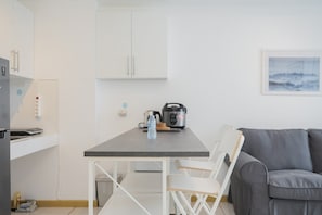 A modern kitchen with white cabinets, a grey countertop, and a grey sofa.