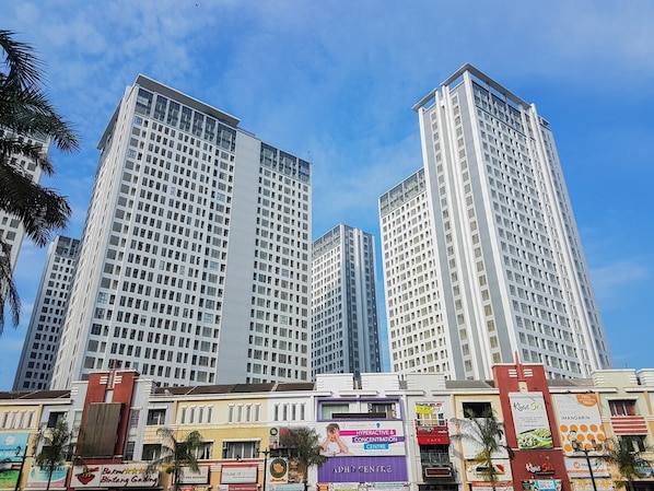 A high-rise building with multiple floors, surrounded by other buildings and palm trees.