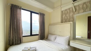 Une chambre d’hôtel avec un lit, une fenêtre avec des rideaux, une table de chevet et un miroir.