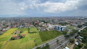 Une vue aérienne d’une ville, avec ses quartiers résidentiels, ses espaces verts et un imposant bâtiment bleu qui se distingue.