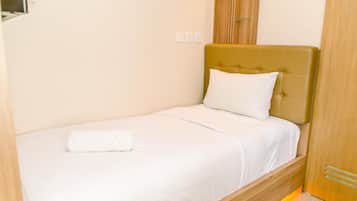 A single bed with a wooden headboard, white bedding, and a white pillow.