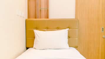 A bed with a headboard, a white pillow, and a wooden wardrobe in the background.