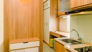 Eine kleine Küche mit Holzschränken, einem Einbauofen, einem Spülbecken und einer Arbeitsplatte.