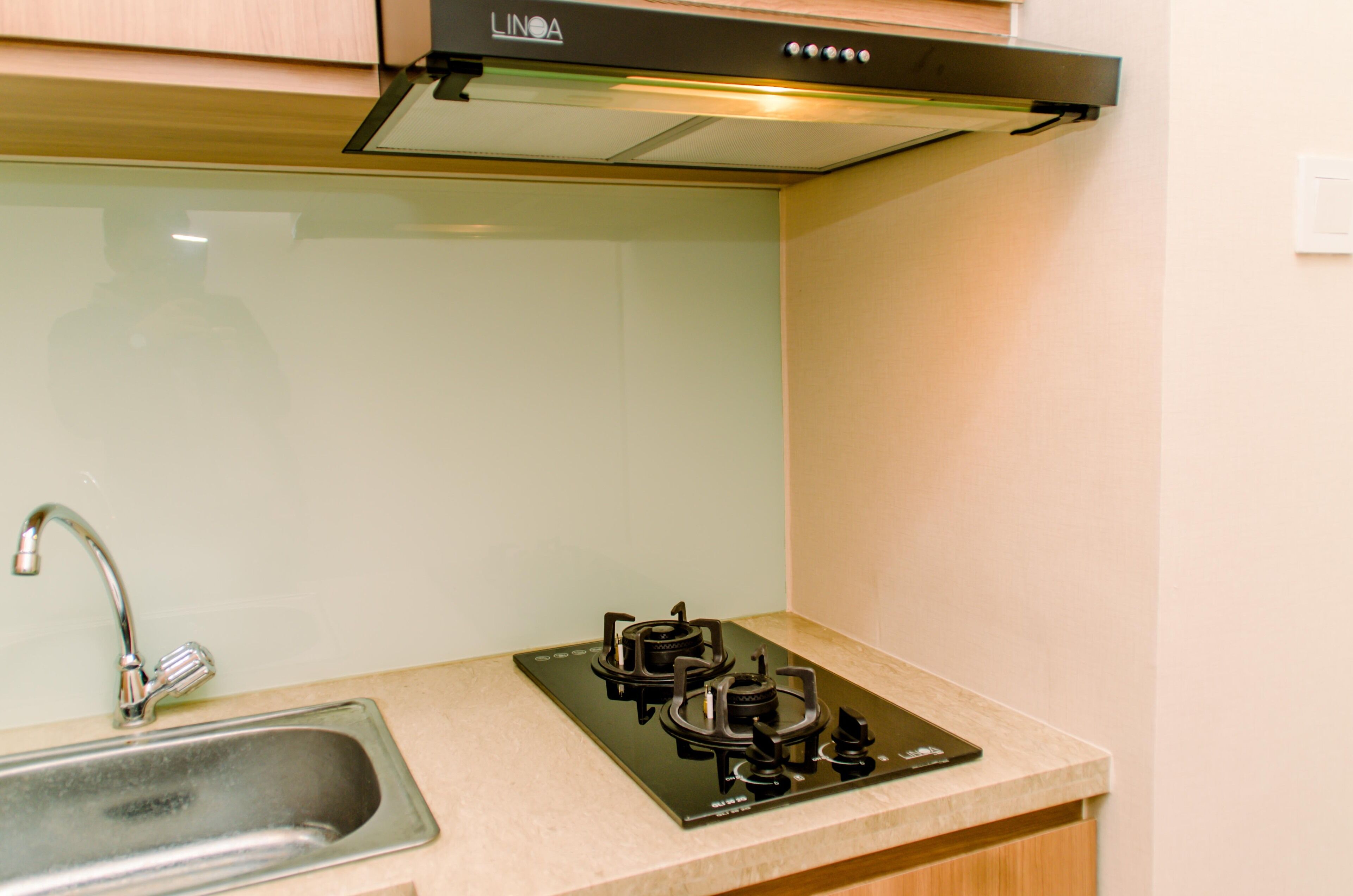 A kitchen with a stainless steel sink, a black gas stove, and a light-colored countertop.