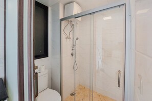 Ein modernes Badezimmer mit einer Duschkabine aus Glas, einer Toilette und einem Spiegel.