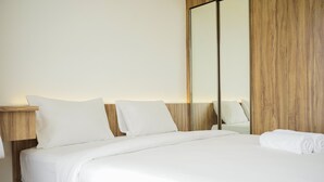 A neatly made bed with white linens, a wooden headboard, and a large mirror on the wall. - Fully Furnished With Pleasure Tidy 2Br At Sky House Bsd Apartment (Pagedangan)