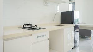 A modern kitchen with white cabinetry, a black refrigerator, and a built-in oven. - Fully Furnished With Pleasure Tidy 2Br At Sky House Bsd Apartment (Pagedangan)