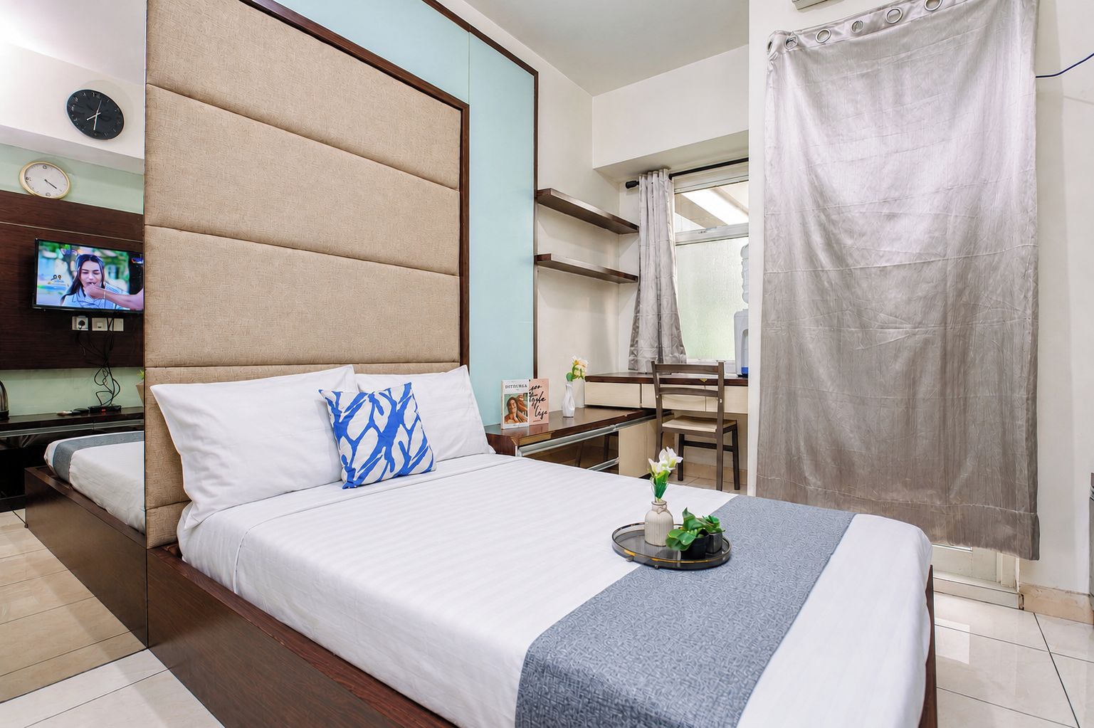 A hotel room with a bed, a television, a desk, and a shower curtain.