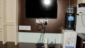 A flat-screen TV mounted on a wooden wall, connected to a power strip with multiple devices plugged in. - Fancy Studio At Springlake Summarecon Bekasi Apartment (Bekasi)