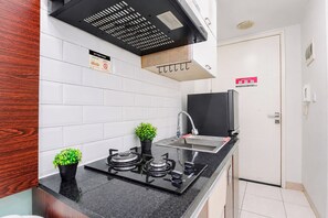 A modern kitchen with a gas stove, a sink, and a black range hood. There are two potted plants on the counter.