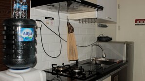 A kitchen with a gas stove, a sink, and a water dispenser. - Fancy Studio At Springlake Summarecon Bekasi Apartment (Bekasi)