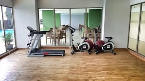 A gym with a treadmill, stationary bikes, and a rowing machine. - Bright And Relaxing 2Br At Mekarwangi Square Bandung (Bandung)