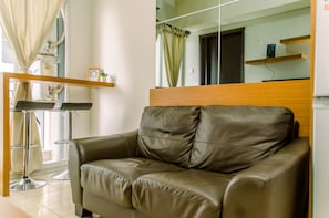 Un salon moderne avec un canapé en cuir, une tête de lit en bois et une table basse en verre.