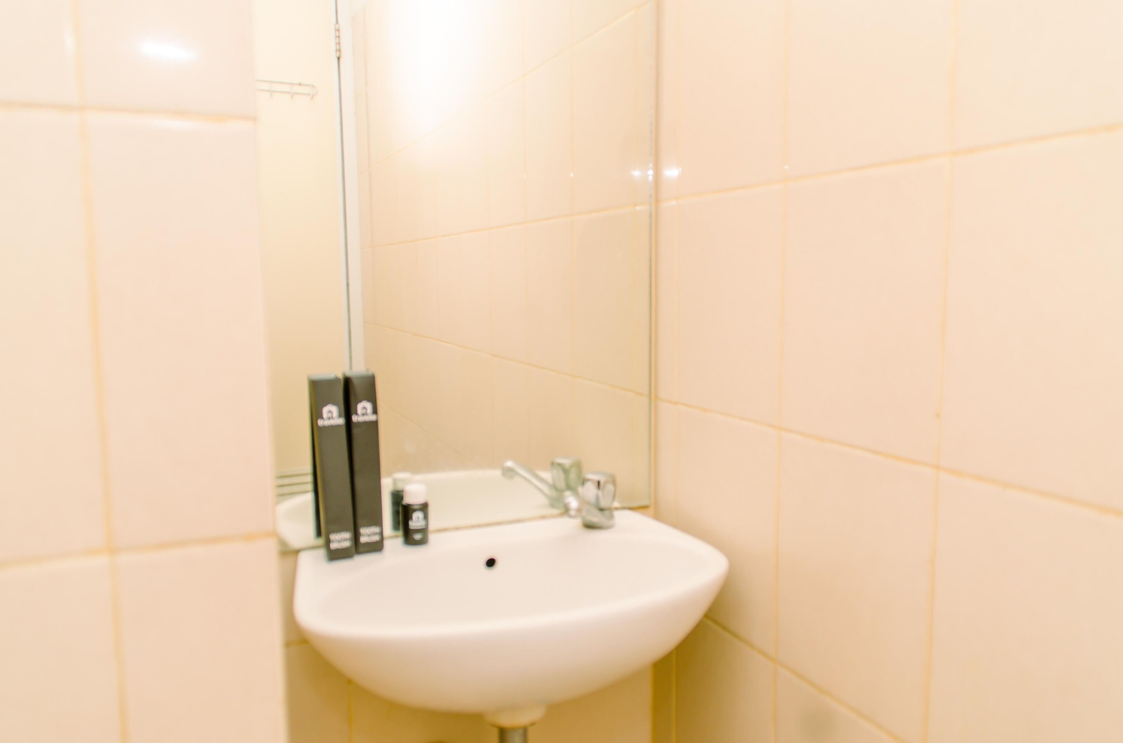 Ein Badezimmer mit einem weißen Waschbecken, einem Spiegel und Toilettenartikeln auf dem Waschbecken.