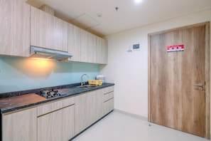 A kitchen with wooden cabinets, a gas stove, a sink, and a wooden door with a fire safety sign.