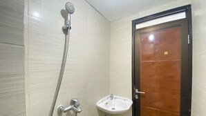 A bathroom with a shower, sink, and wooden door. - Cozy Studio Apartment At Gateway Pasteur Bandung (Cimahi)